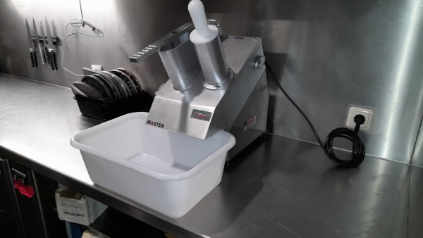 De nieuwe Master horeca snijmachine op een RVS werkblad met messen en opvangbak.