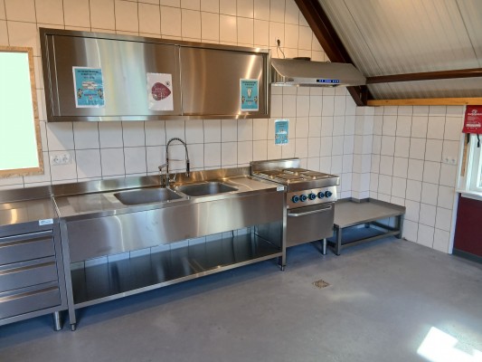Rechtergedeelte van de keuken met afzuigkap en kleine werktafel voor hoge pannen