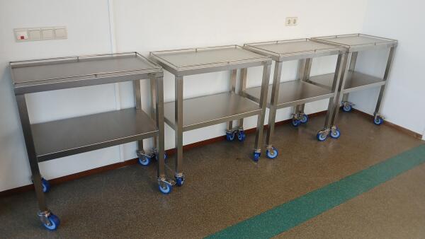 Vier stuks verrijdbare RVS bijzettafels op een rij.