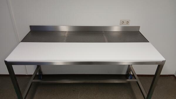 Werkblad van een RVS werktafel met voor een kunststof snijblad voor vlees en achter in het blad een geperforeerde plaat, waar het vocht door heen kan lekken.