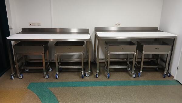 4 verrijdbare RVS frames met passende bakken met verrijdbare RVS werktafel met kunststof snijblad voor vlees en afvalgedeelte.